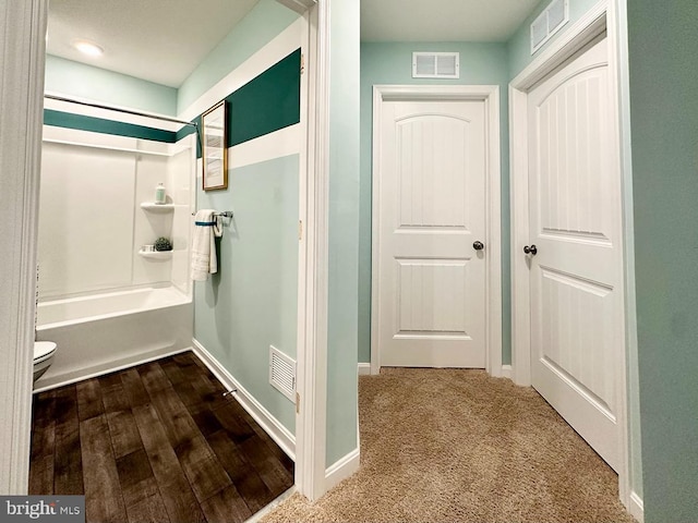 bathroom with toilet, wood-type flooring, and shower / washtub combination