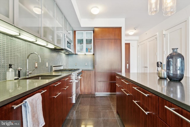 kitchen featuring decorative light fixtures, dark tile patterned floors, sink, stainless steel range, and decorative backsplash