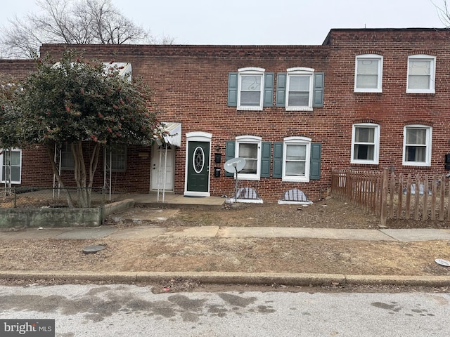 view of property featuring brick siding and fence