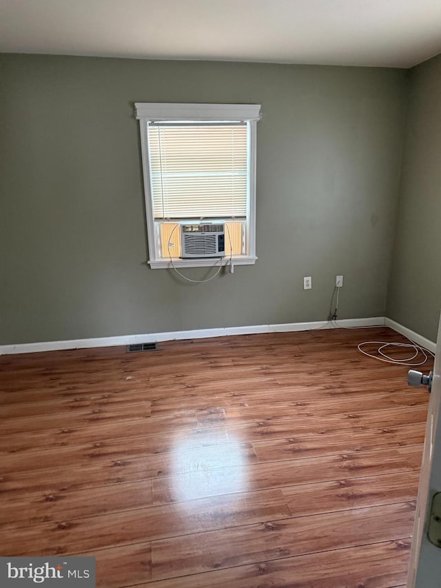 empty room featuring baseboards, visible vents, cooling unit, and wood finished floors