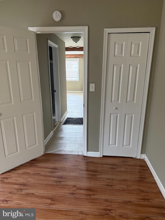 corridor with baseboards and wood finished floors