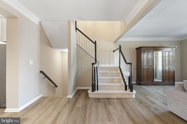 staircase with ornamental molding, wood finished floors, and baseboards