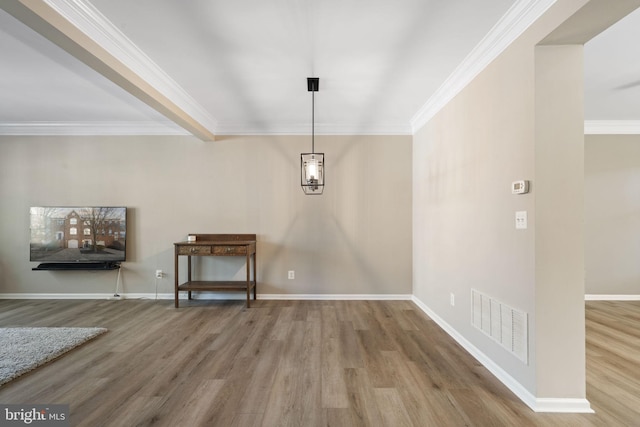 unfurnished dining area featuring visible vents, crown molding, baseboards, and wood finished floors