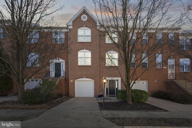 view of property with concrete driveway, brick siding, and an attached garage