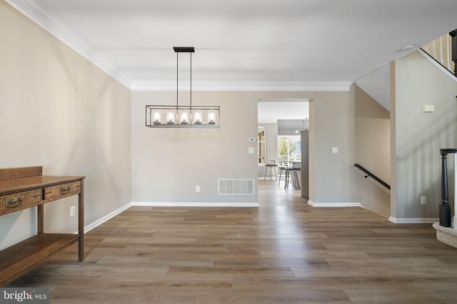 dining area with baseboards, wood finished floors, visible vents, and crown molding