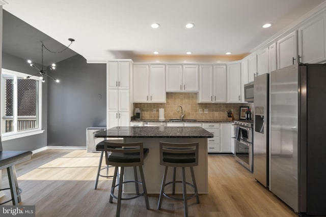 kitchen featuring stainless steel appliances, backsplash, a sink, and light wood-style flooring