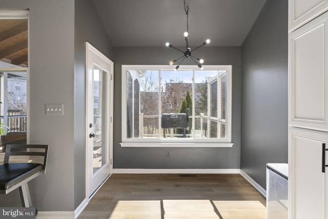 unfurnished dining area with a notable chandelier, baseboards, and wood finished floors