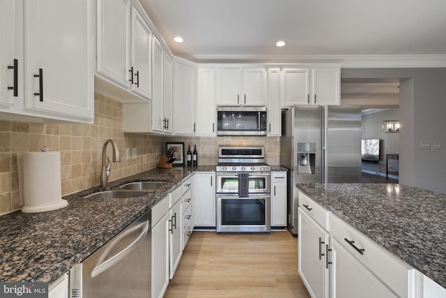 kitchen featuring stainless steel appliances, a sink, white cabinetry, light wood-type flooring, and crown molding