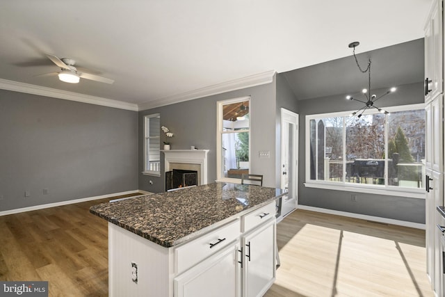 kitchen featuring dark stone counters, a lit fireplace, plenty of natural light, and light wood-style floors