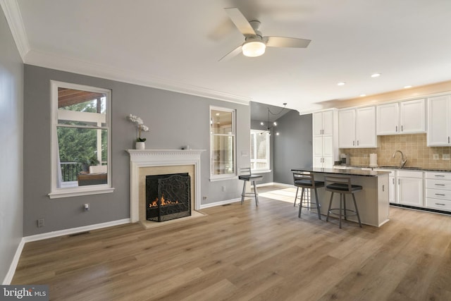 kitchen with tasteful backsplash, visible vents, light wood-style flooring, white cabinetry, and a kitchen island