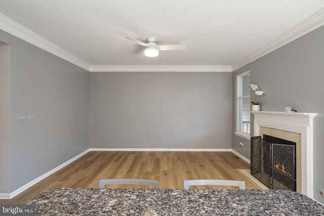 unfurnished living room with ornamental molding, wood finished floors, a fireplace with flush hearth, and baseboards