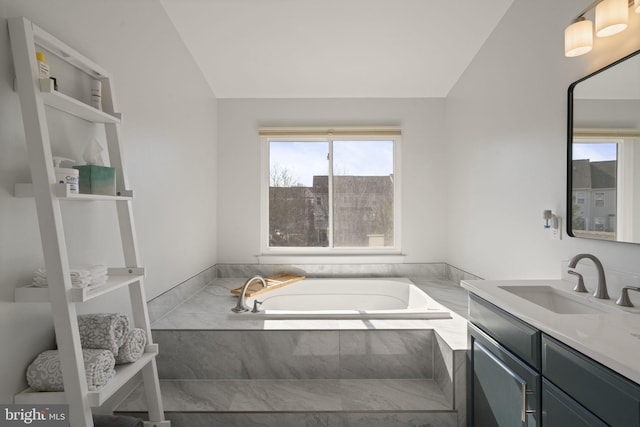 bathroom featuring lofted ceiling, vanity, and a bath