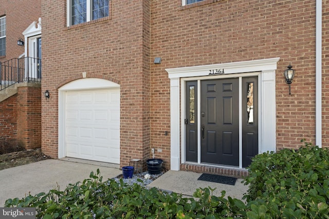 entrance to property featuring a garage and brick siding