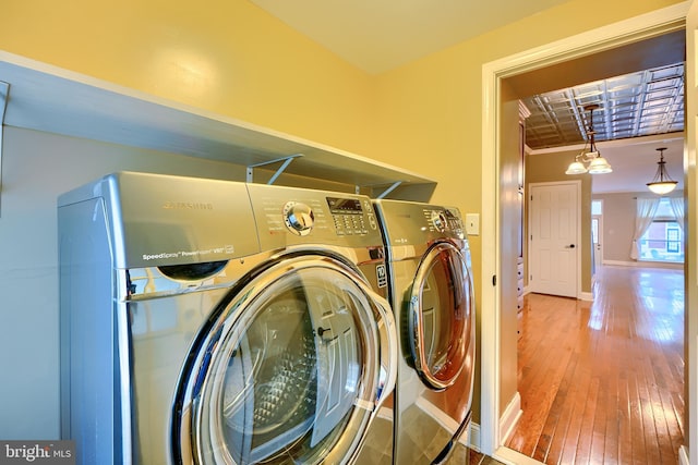 laundry room featuring hardwood / wood-style flooring, laundry area, baseboards, washer and clothes dryer, and crown molding