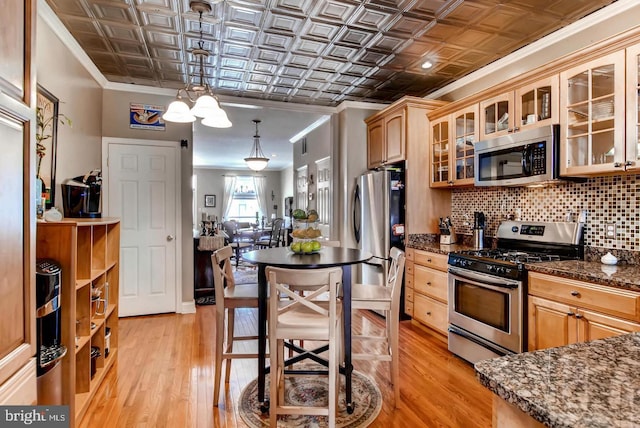 kitchen with an ornate ceiling, light wood finished floors, stainless steel appliances, backsplash, and ornamental molding