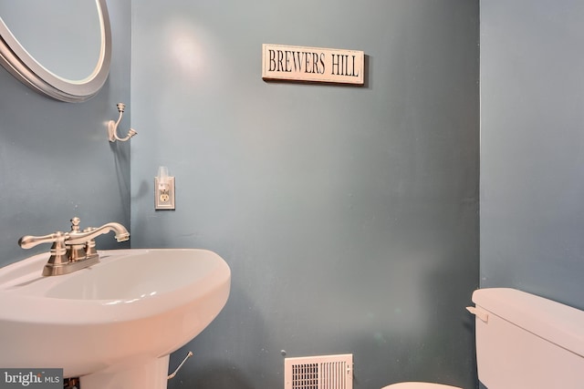 half bath featuring visible vents, a sink, and toilet