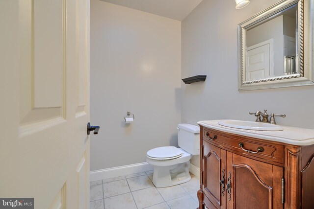 bathroom with toilet, vanity, baseboards, and tile patterned floors