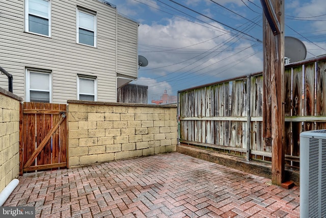 view of patio / terrace with a gate, fence, and central AC unit