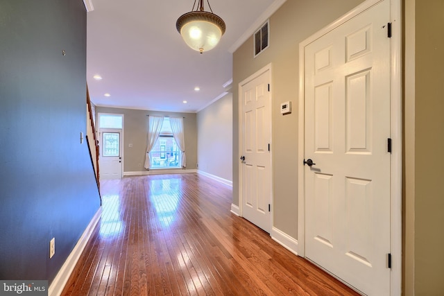 corridor with visible vents, baseboards, hardwood / wood-style flooring, crown molding, and recessed lighting