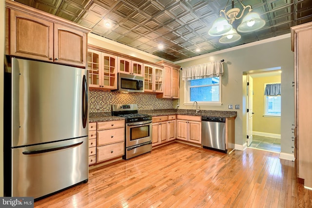 kitchen with stainless steel appliances, a sink, baseboards, decorative backsplash, and an ornate ceiling