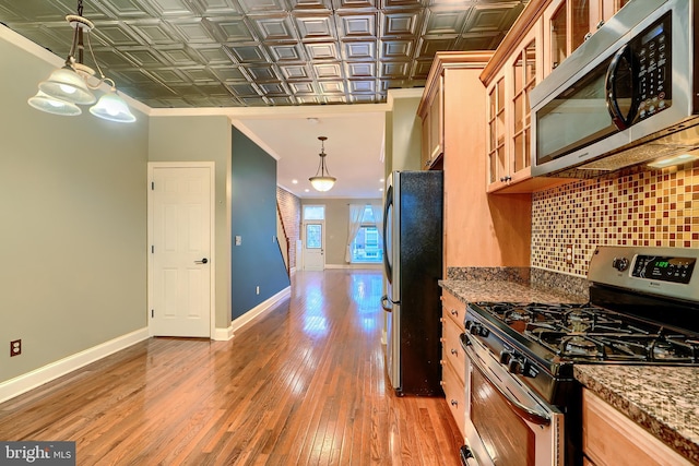 kitchen with an ornate ceiling, light wood finished floors, decorative backsplash, appliances with stainless steel finishes, and baseboards