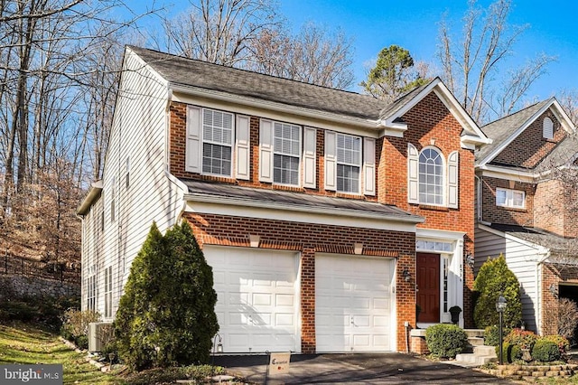 traditional-style house featuring an attached garage, aphalt driveway, and brick siding