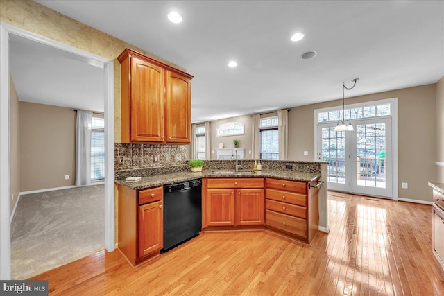 kitchen featuring black dishwasher, brown cabinets, a peninsula, and light wood finished floors