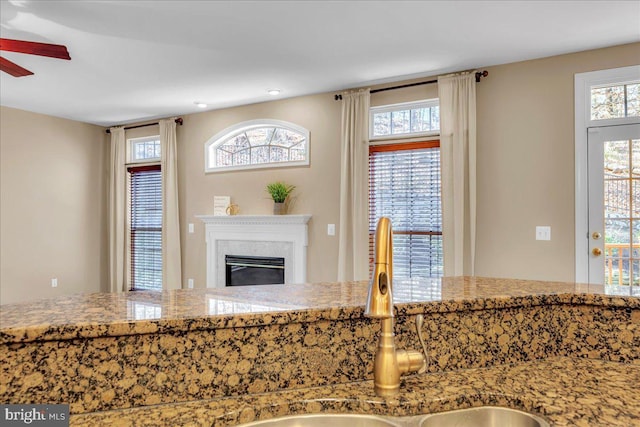 kitchen with a glass covered fireplace, stone counters, and a sink