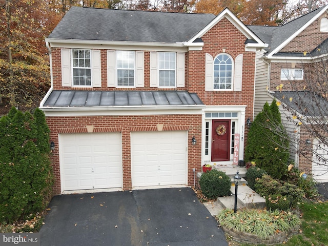 view of front of property with driveway, a garage, metal roof, a standing seam roof, and brick siding