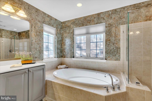 bathroom featuring a stall shower, vanity, and a bath