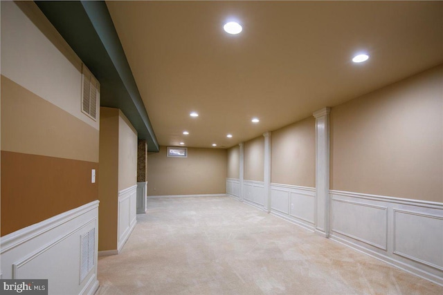 interior space with a decorative wall, recessed lighting, visible vents, and light colored carpet