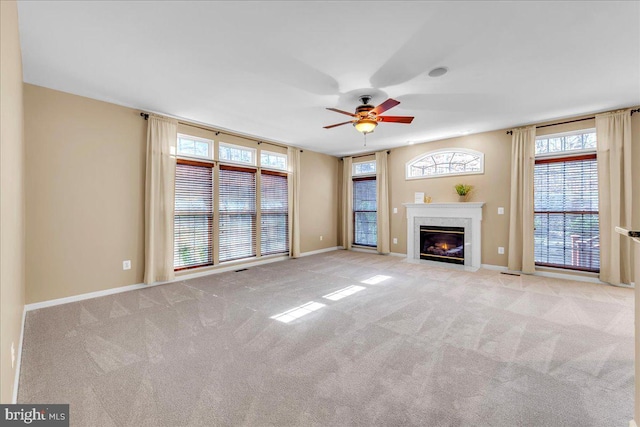 unfurnished living room featuring a premium fireplace, carpet, a ceiling fan, and baseboards