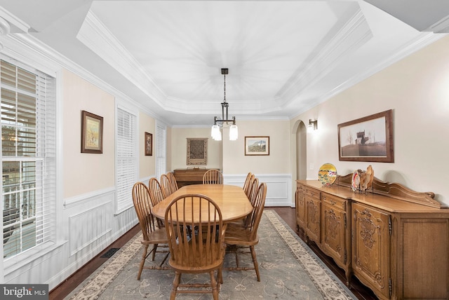 9801 Alydar Ct, Nokesville, VA 20181 - dining space featuring a wainscoted wall, dark wood-type flooring, a notable chandelier, a tray ceiling, and arched walkways