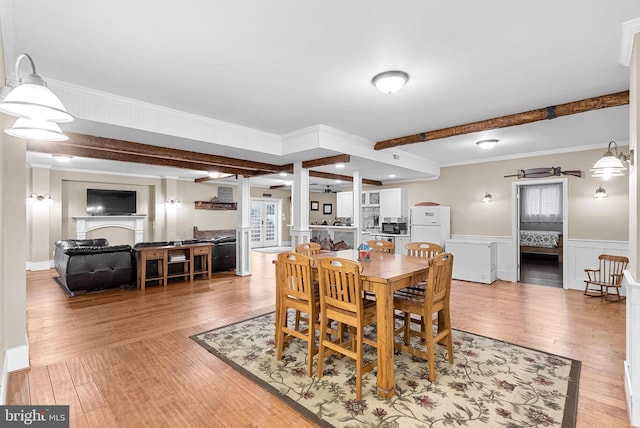 9801 Alydar Ct, Nokesville, VA 20181 - dining space featuring beamed ceiling, a wainscoted wall, light wood-type flooring, ornamental molding, and a fireplace