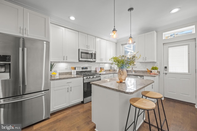 kitchen featuring a kitchen bar, dark wood-type flooring, a kitchen island, white cabinetry, and appliances with stainless steel finishes