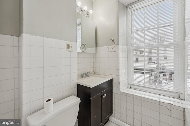 bathroom with toilet, tile walls, and vanity