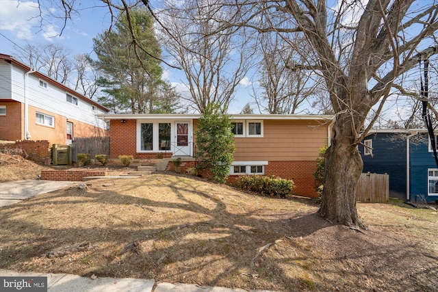 view of front of house with entry steps, fence, and brick siding