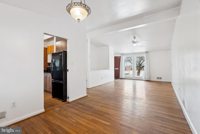 unfurnished living room with ceiling fan, visible vents, hardwood / wood-style flooring, and baseboards