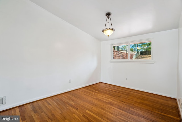 empty room with baseboards, visible vents, and hardwood / wood-style floors