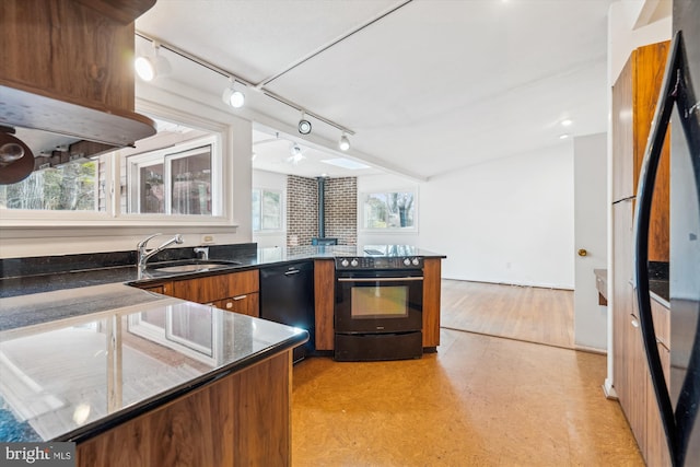 kitchen with brown cabinets, light floors, a peninsula, black appliances, and a sink