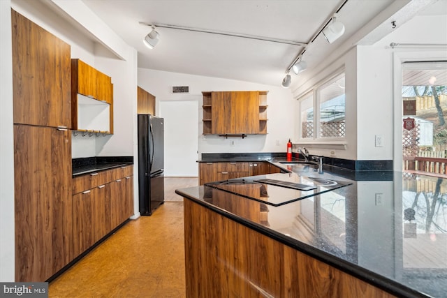 kitchen featuring brown cabinets, open shelves, track lighting, and freestanding refrigerator