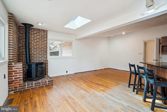 living room with visible vents, wood-type flooring, a wood stove, and baseboards