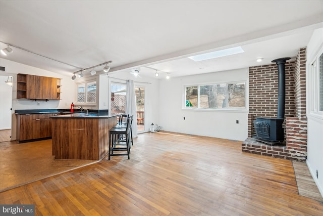 kitchen featuring dark countertops, a wood stove, light wood-style flooring, and open shelves