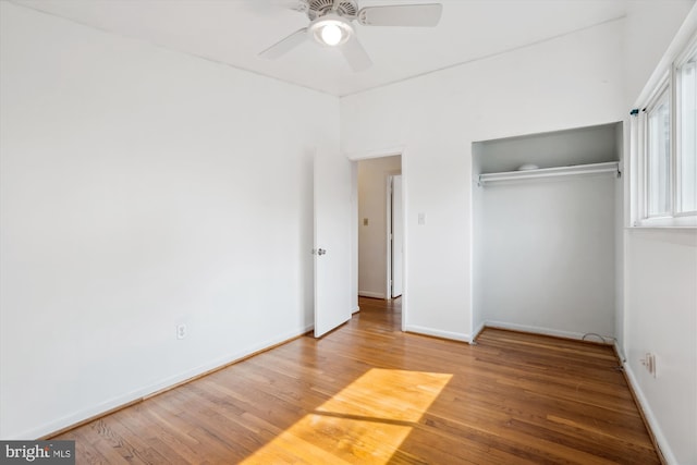 unfurnished bedroom featuring a closet, wood finished floors, a ceiling fan, and baseboards