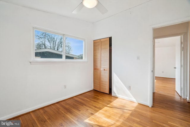 unfurnished bedroom featuring light wood-style floors, a ceiling fan, baseboards, and a closet