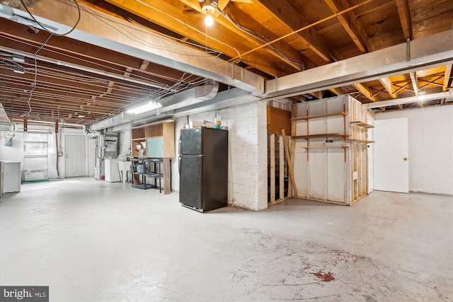 unfinished basement with freestanding refrigerator