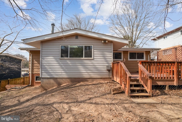 rear view of house featuring fence and a deck