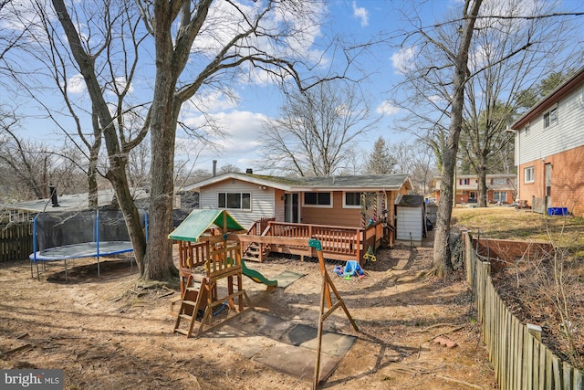 back of house with a trampoline, fence, a playground, and a wooden deck