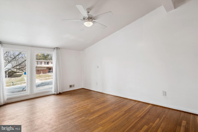 spare room featuring lofted ceiling, visible vents, ceiling fan, baseboards, and hardwood / wood-style flooring