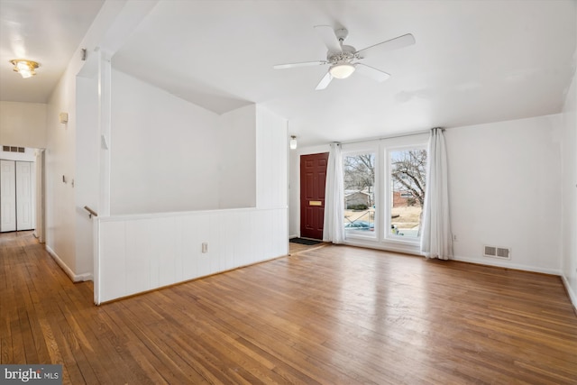 spare room with lofted ceiling, wood-type flooring, visible vents, a ceiling fan, and baseboards